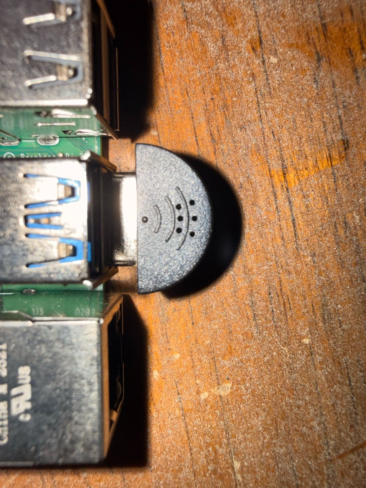 Close-up of a tiny half-round black USB microphone plugged directly into a Raspberry Pi USB port